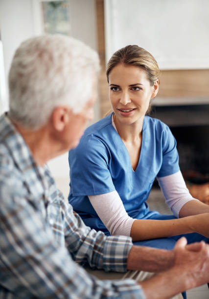 Shot of a female nurse and her senior patient chatting in the living room